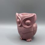 A hand-finished owl planter with closed eyes and detailed feathers, rendered in a metallic rose quartz pink shimmer against a neutral grey background
