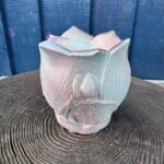 An ornate planter shaped like a lotus flower with a textured metallic pink and gold gradient finish.