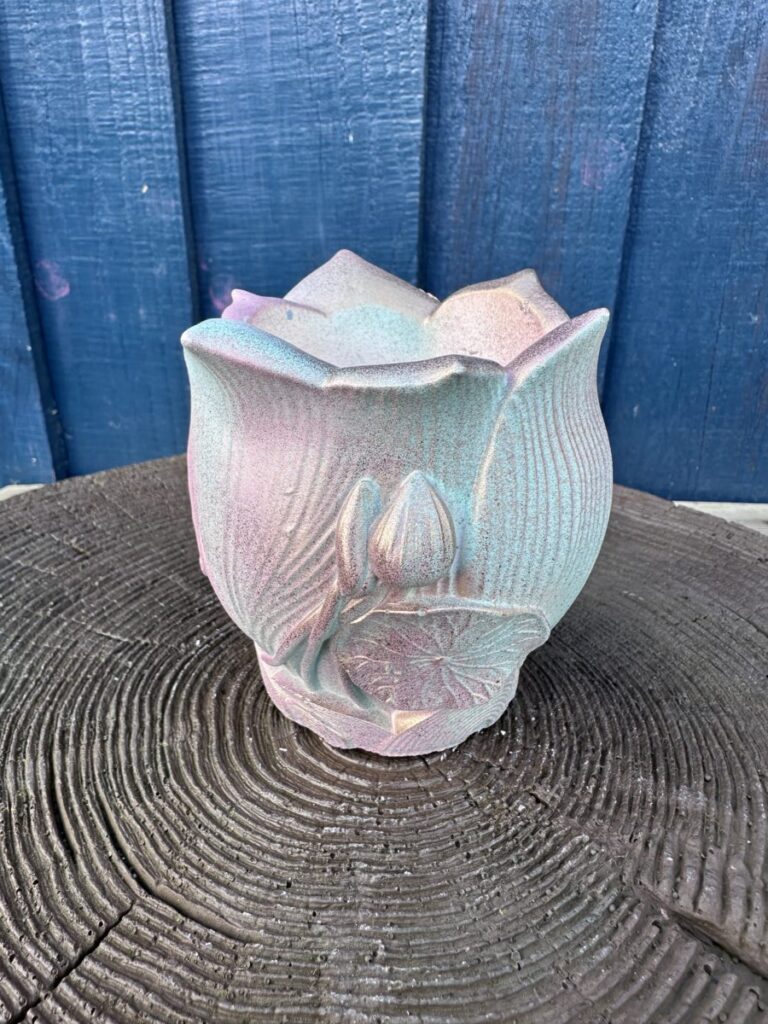 An ornate planter shaped like a lotus flower with a textured metallic pink and gold gradient finish.