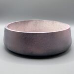 A wide, shallow round planter with a dark, speckled texture transitioning from a charcoal base to a deep purple iridescent rim.