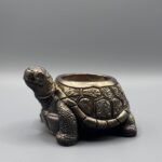 Small decorative tortoise-shaped planter with an antiqued bronze finish and detailed shell carvings, shown against a grey background.
