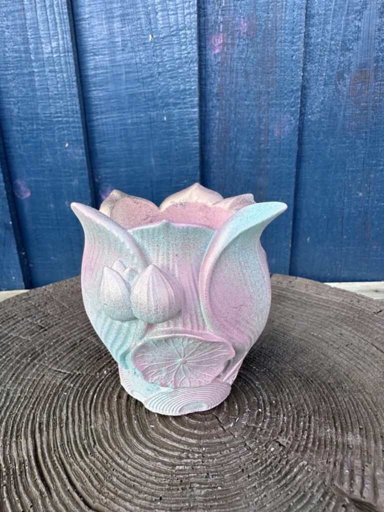 An ornate planter shaped like a lotus flower with a textured metallic pink and gold gradient finish.