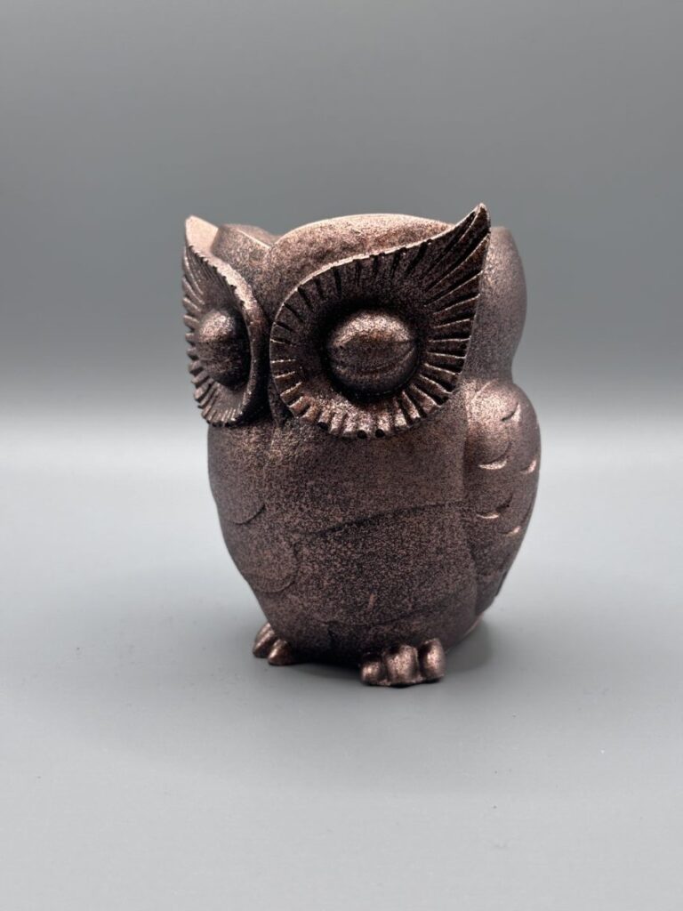 A front-facing view of a handcrafted owl planter with a deep metallic bronze finish, featuring detailed fanned patterns around the eyes and a textured surface.