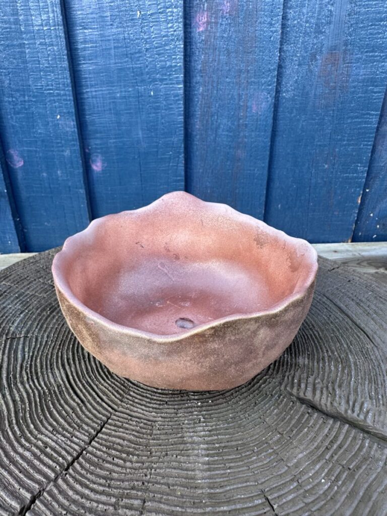 Gemini said This piece for Boba's Plant offers a beautiful, grounded contrast to the more intricate designs in your collection. Its raw, organic energy makes it an ideal home for a desert succulent or a minimalist moss arrangement. Product Title Desert Ember: Raw Edge Terracotta Stone Basin The Description Embrace the beauty of imperfection with this hand-crafted basin, featuring a rugged, undulating rim that mimics the natural erosion of desert canyons. The texture is wonderfully dualistic: a smooth, matte interior bowl paired with a coarse, weathered exterior that feels like ancient sun-baked earth. Its wide, low-profile silhouette provides a grounded "wabi-sabi" vibe, perfect for creating a miniature landscape or a focused botanical statement. Color-Specific Snippets Rustic Terracotta: A deep, warm clay base with subtle variations in earth-toned pigment. Toasted Umber Accents: Darker, scorched-earth tones along the base and rim for added depth. Matte Clay Finish: A non-reflective, natural surface that highlights the raw mineral quality of the piece. Specific Product Tags Organic Basin Terracotta Decor Wabi-Sabi Style Hand-Cast Planter Succulent Bowl Desert Aesthetic Artisan Stoneware Minimalist Planter SEO Keywords Primary: Low profile succulent bowl, rustic terracotta planter, organic edge stone basin. Secondary: Handmade clay pot, wide mouth planter, earthy home decor, wabi-sabi garden art. Yoast-Ready Meta Description Discover the Desert Ember Basin at Boba's Plant. This hand-cast terracotta-toned planter features a raw, organic edge and a weathered texture, perfect for minimalist and desert-inspired plant styling. Alt Text A wide, shallow hand-cast planter bowl with a rustic terracotta color and an irregular, wavy rim, displayed on a textured dark wood surface against a blue wooden backdrop.