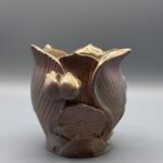 An ornate planter shaped like a lotus flower with a textured metallic pink and gold gradient finish.