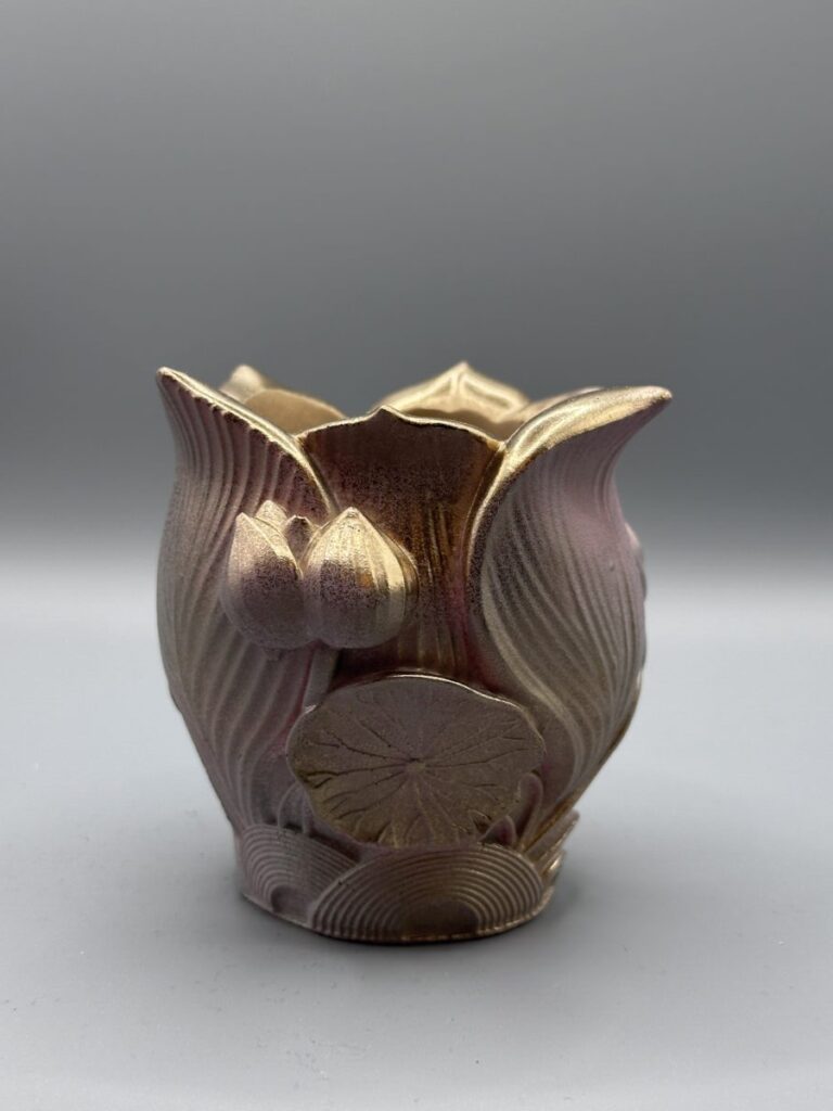 An ornate planter shaped like a lotus flower with a textured metallic pink and gold gradient finish.