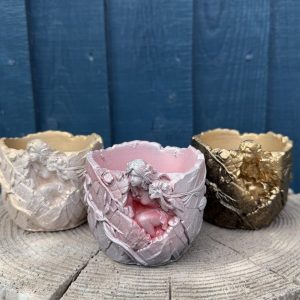 Hand-cast fairy planter in blush pink, a sleeping fairy wrapped in cast leaves, on a wooden log
