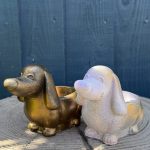 Hand-cast long-eared puppy planter in antique gold, head raised with ears hanging down, on a wooden log