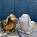 Hand-cast long-eared puppy planter in antique gold, head raised with ears hanging down, on a wooden log