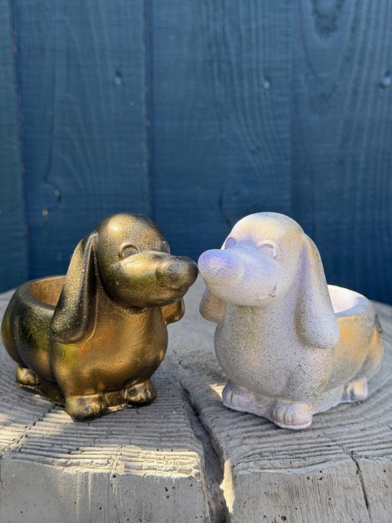 Hand-cast long-eared puppy planter in antique gold, head raised with ears hanging down, on a wooden log