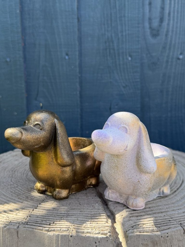 Hand-cast long-eared puppy planter in antique gold, head raised with ears hanging down, on a wooden log