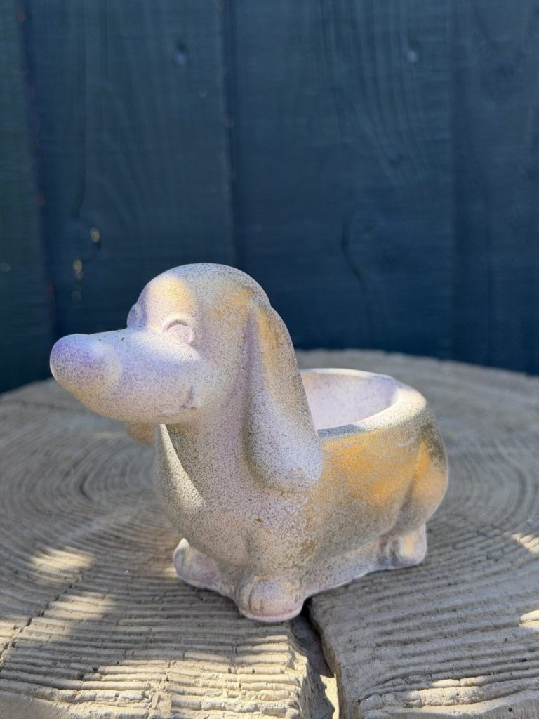 Hand-cast long-eared puppy planter in pearl white, head raised with ears hanging down, on a wooden log