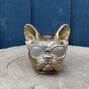 Hand-cast French bulldog planter in antique gold with a silver face, wearing sunglasses, on a wooden log