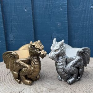 Hand-cast guardian dragon planter in antique silver, a winged dragon curled around a shallow bowl, on a wooden log