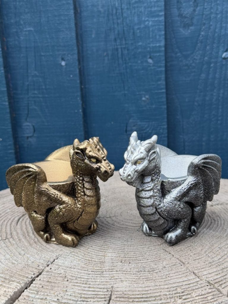 Hand-cast guardian dragon planter in antique silver, a winged dragon curled around a shallow bowl, on a wooden log